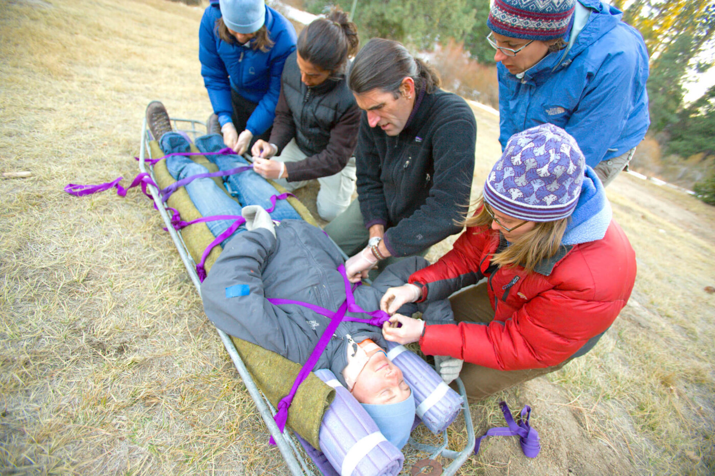 Wilderness rescue students practicing learned skills on a patient in a gurney.